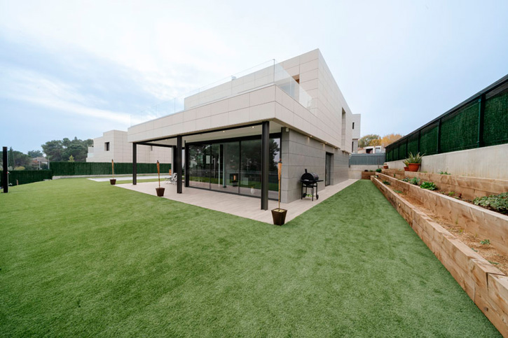 Fachada posterior de la casa MP17 con porche, grandes ventanales y jardín en l’Ametlla del Vallès