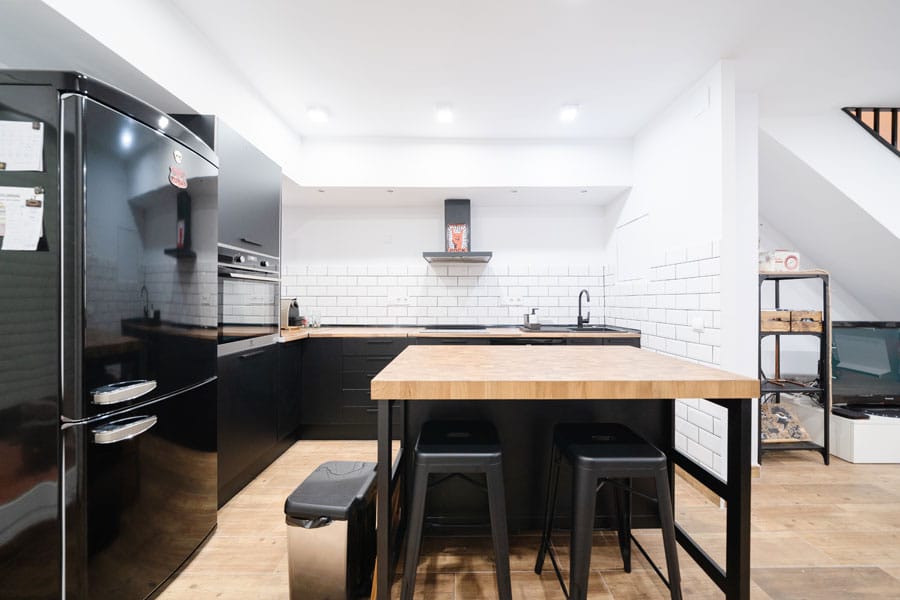 Cocina abierta con los muebles negros en una reforma con cambio de uso