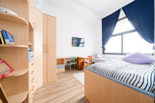 Habitación de niños con dos camas y armario en proyecto de cambio de uso