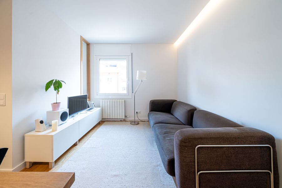 Salón con sofá en reforma integral con afectación estructural en Barcelona