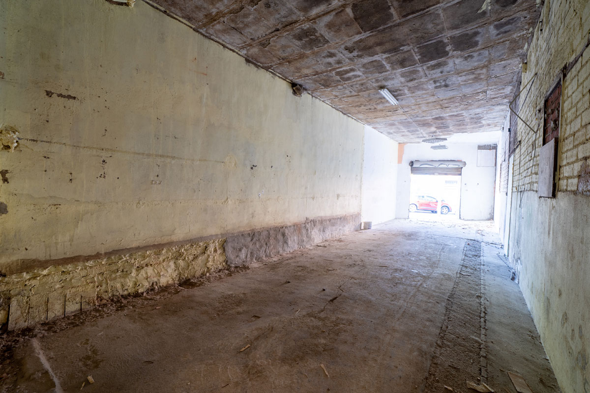 Espacio original en Sabadell antes de la reforma y cambio de uso, con paredes deterioradas, techo de hormigón y suelo sin acabados.