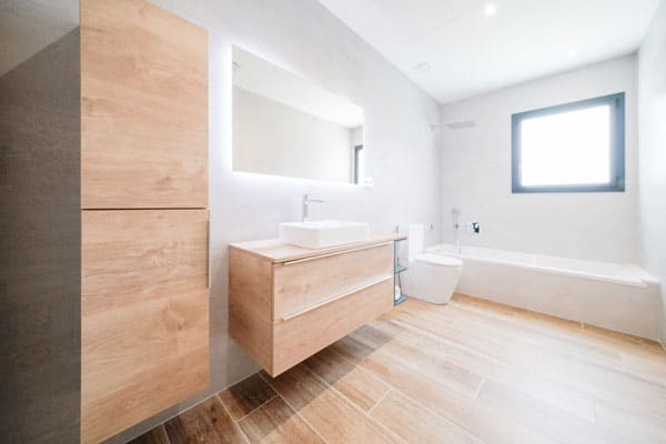 Espacio de baño luminoso y funcional en casa unifamiliar sana y eficiente, con acabados en madera y hormigón celular respetuoso con el medio ambiente.