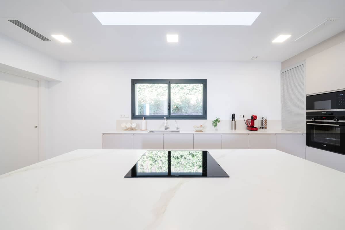 Cocina moderna y saludable en vivienda eficiente de l'Ametlla del Vallès, con isla central y luz natural cenital que aporta bienestar y confort.