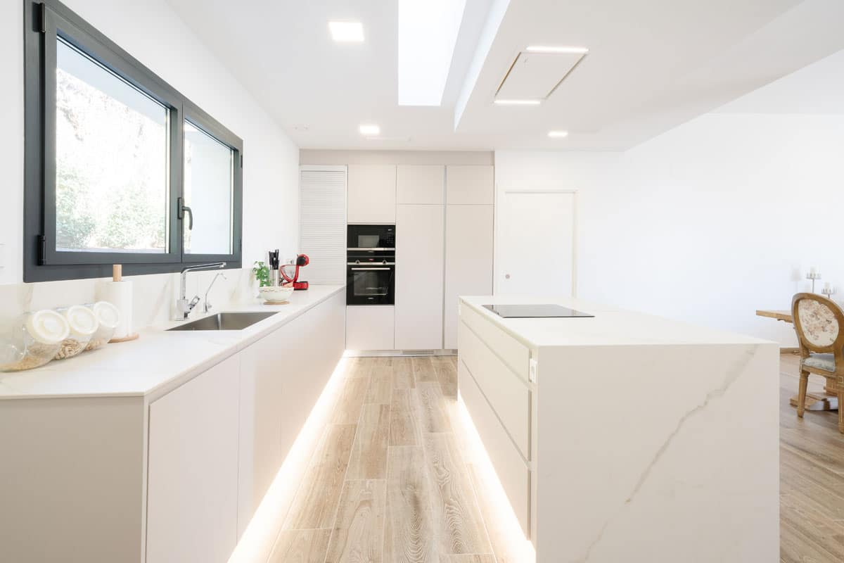 Cocina abierta con isla de líneas limpias, espacio luminoso y saludable en casa eficiente de hormigón celular, diseñada para disfrutar en familia con confort y respeto al medio ambiente.
