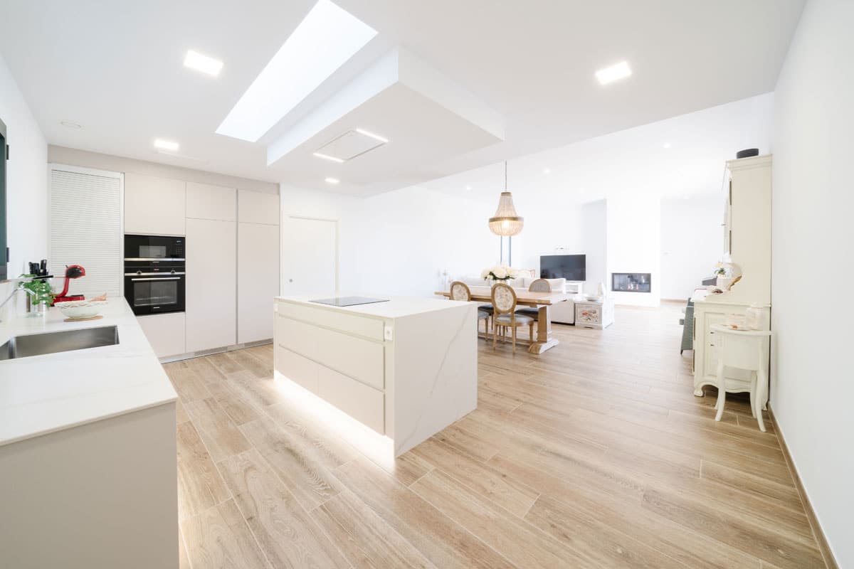 Cocina moderna con isla central y comedor integrado en vivienda saludable y eficiente en l’Ametlla del Vallès, diseñada con espacios amplios, luminosos y conectados para el bienestar familiar.