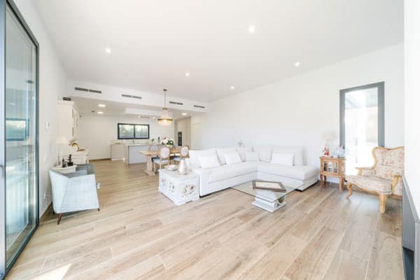 Salón luminoso con chimenea y grandes ventanales en vivienda saludable en l’Ametlla del Vallès, conectado al porche y al jardín.