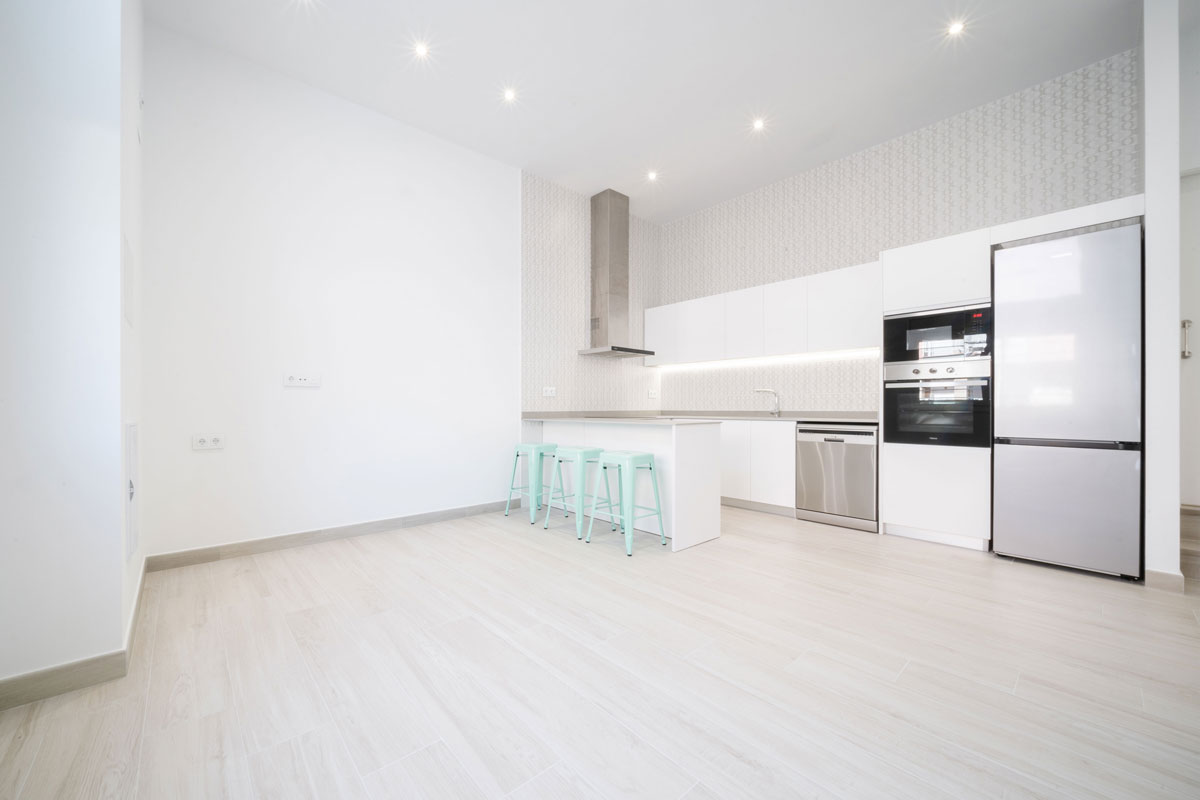 Cocina blanca con península en cambio de uso de bar a vivienda en Mollet