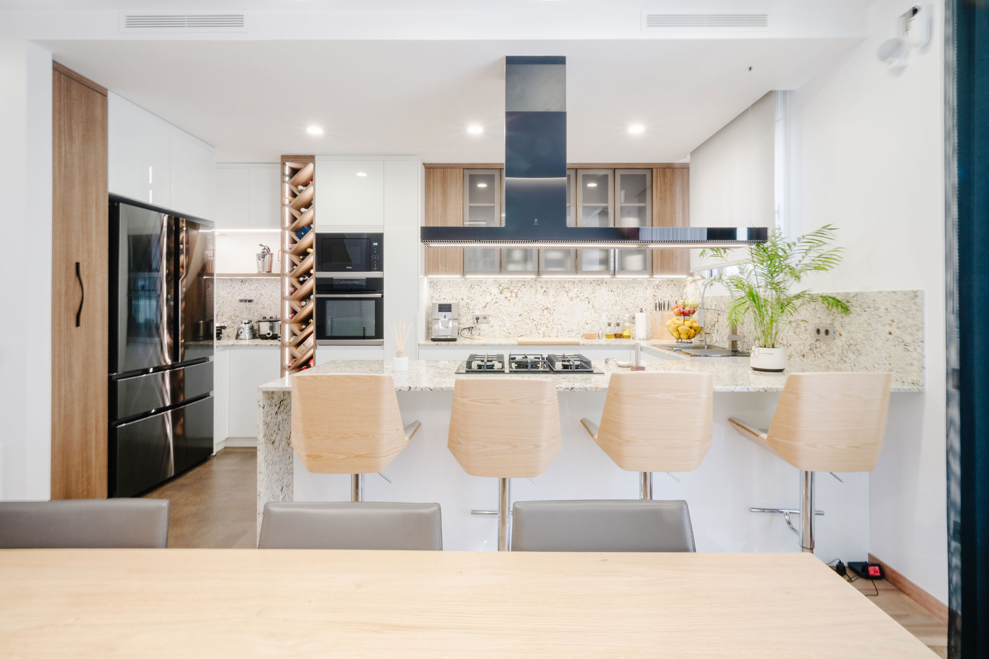 Cocina abierta con gran península y cuatro taburetes