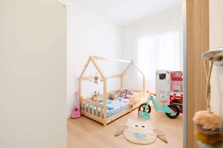 Dormitorio infantil reformado con cama de madera y zona de juegos