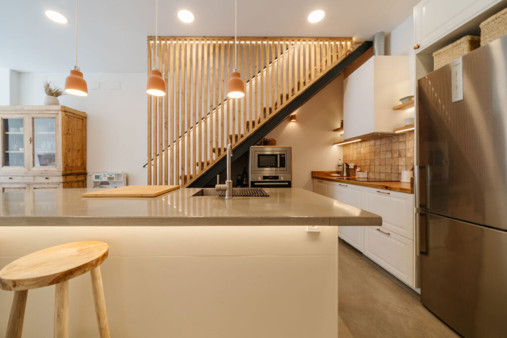 Cocina con isla y escalera de madera en edificio histórico rehabilitado