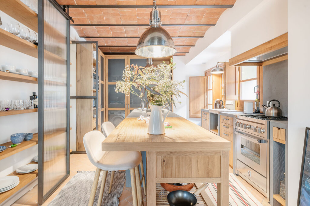 Cocina con gran isla de madera, florero central y mobiliario a medida en reforma de vivienda histórica