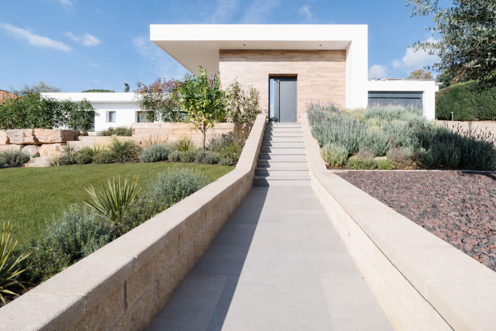 Escalera central de acceso a casa unifamiliar entre jardines mediterráneos