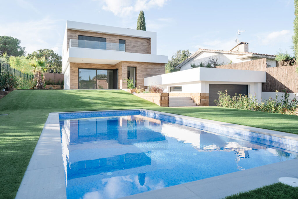 Piscina en primer plano frente a vivienda unifamiliar moderna